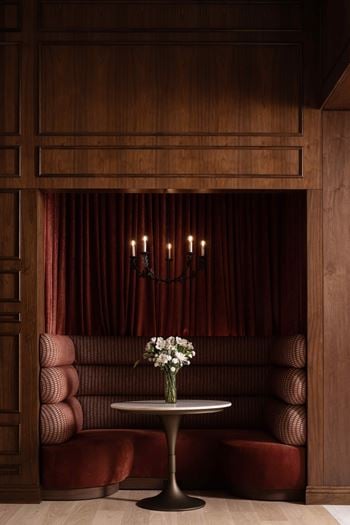 A table with a vase of flowers on it in front of a red sofa